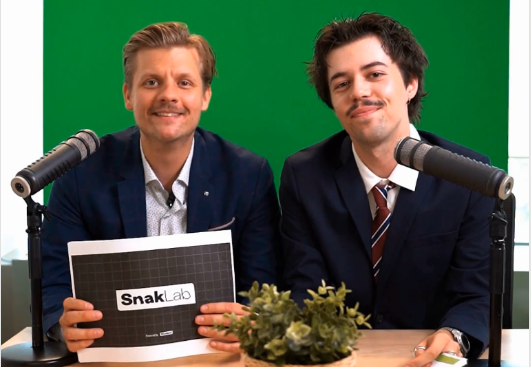 SnakNews: this was Q2 at SnakLab | SnakLab Two SnakLab hosts in suits behind podcast microphones in front of a green screen, ready to record SnakNews Q2.